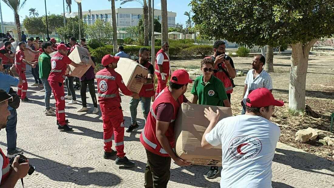 humanitarian aid workers handing out large boxes in the Gaza crisis